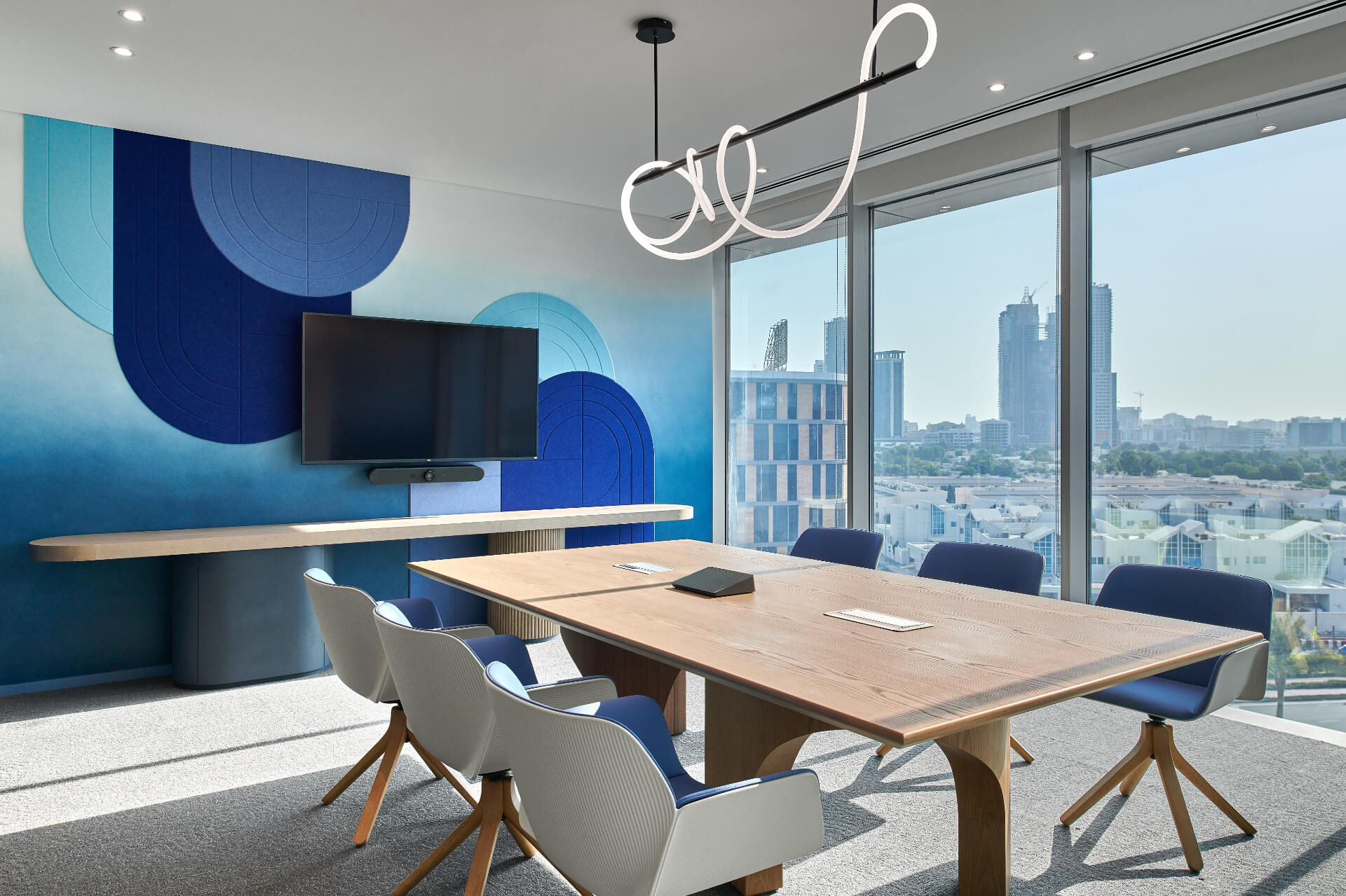 Conference room overlooking cityscape with blue painted wall with geometric shapes. Source: https://www.summertown.ae/sustainability-hub/