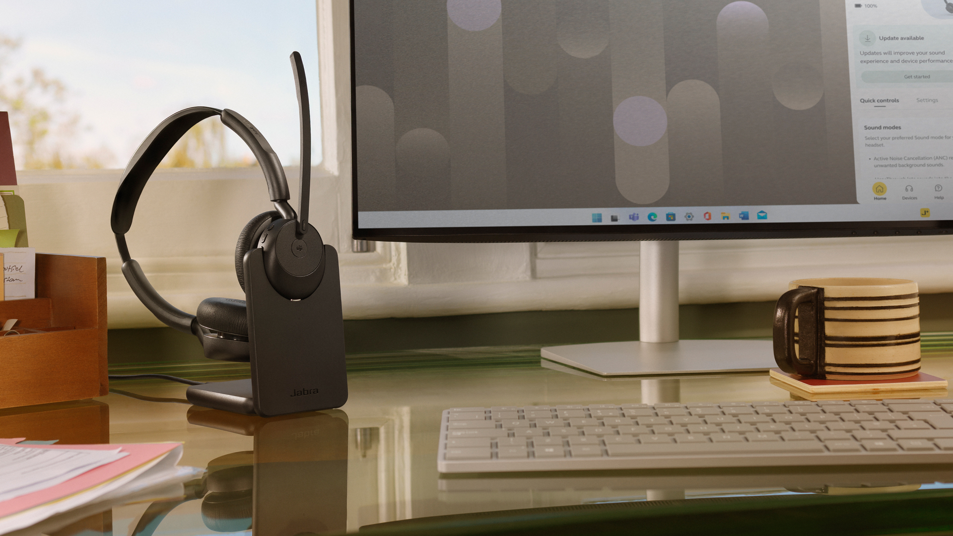 Jabra Evolve3 45 headset docked on a desk next to a monitor and keyboard