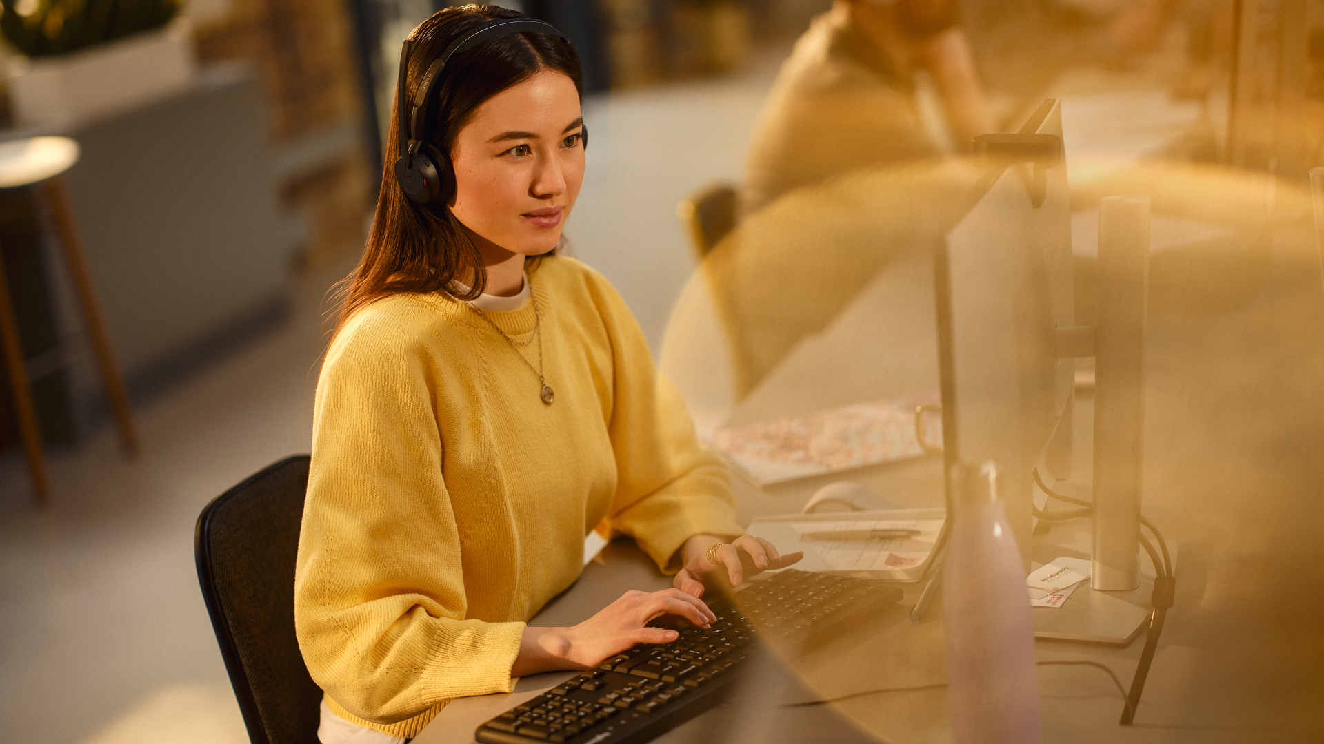 Person wearing Jabra Evolve3 45 headset while working at a computer in an office
