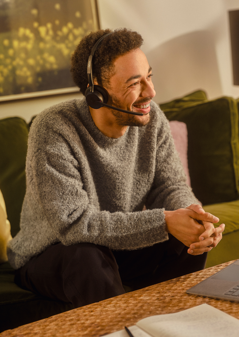 Person wearing Jabra Evolve3 45 headset while seated on a sofa