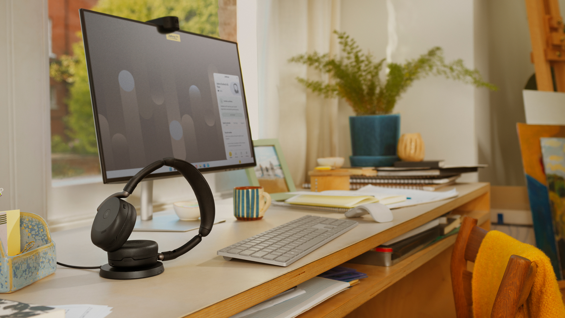 Jabra Evolve3 65 Flex headset on a charging stand in a desk workspace